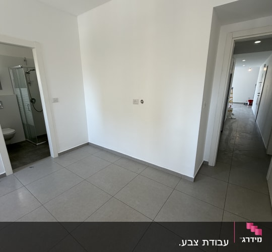 חדר ריק עם קירות לבנים ורצפת אריחים אפורה